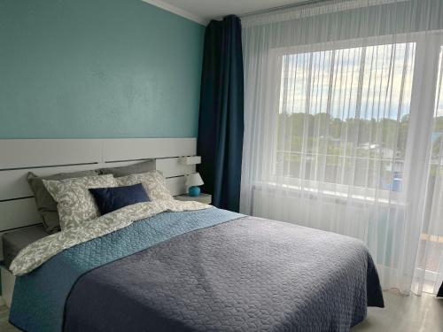 a bedroom with a bed and a large window at Family Nest in Ventspils