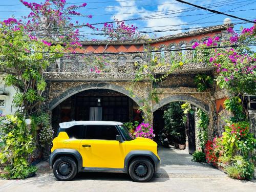 a yellow jeep parked in front of a building with flowers at Sầm Sơn Boutique Hotel Phan Thiết in Phan Thiet