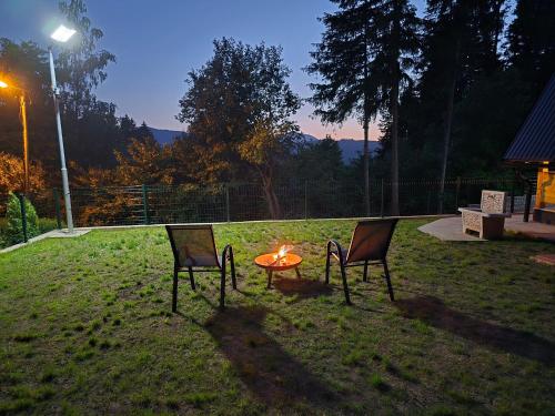 two chairs and a table with a fire in the grass at Vikendica Villa Marija Pale in Pale