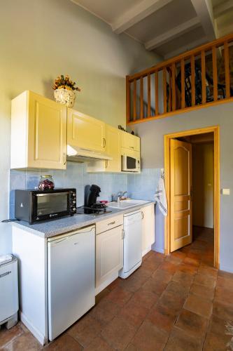 une cuisine avec des armoires blanches et un micro-ondes dans l'établissement Gîte Lavande au milieu des vignes - Chateau les Apiès, aux Arcs-sur-Argens