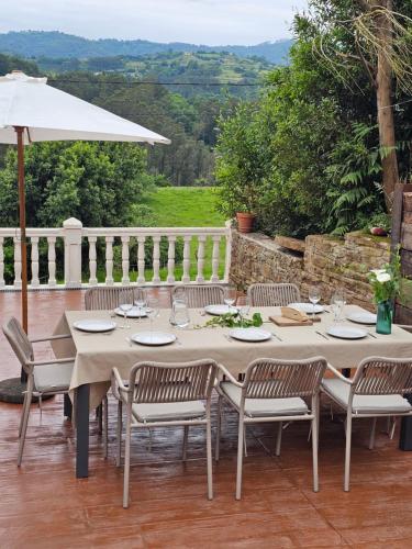 a table with chairs and an umbrella on a patio at Ven al Paraiso! Amanece en Miravalles in Villaviciosa
