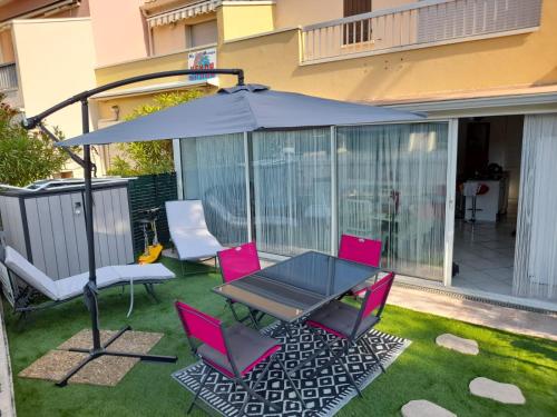 une terrasse avec des chaises roses, une table et un parasol dans l'établissement La Mouette rieuse, au Cap d'Agde