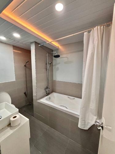 a bathroom with a bath tub and a sink at Cozy Manor with Spacious Kitchen and Tub in General Santos