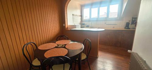 une table de salle à manger avec des chaises et une cuisine dans l'établissement Le Clémille, à Thonon-les-Bains
