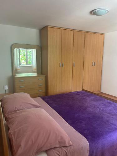a bedroom with a purple bed and wooden cabinets at Apartment Anić in Šmrika