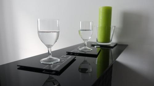 dwa kieliszki i zieloną świeczkę na czarnym stole w obiekcie Apartament 3D w mieście Gdynia