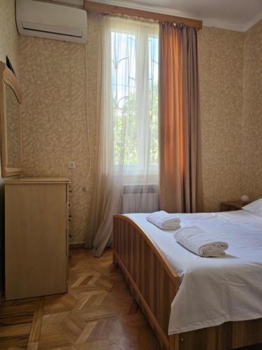 a bedroom with a bed with white sheets and a window at old house in Kutaisi