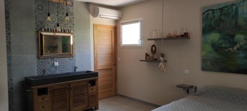 une salle de bain avec un lavabo, un miroir et un lit dans l'établissement Un joli jardin méditerranéen, au Cap d'Agde