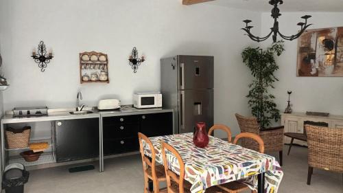 une cuisine avec une table et un réfrigérateur dans l'établissement Un joli jardin méditerranéen, au Cap d'Agde