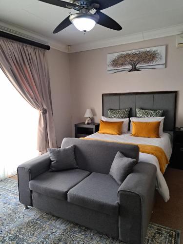 a bedroom with a bed and a couch and a ceiling fan at 28 on Oribi in Welkom