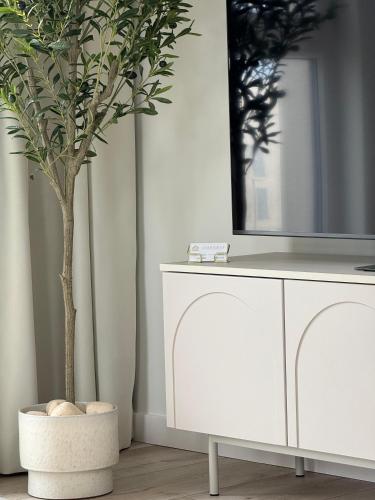 a white cabinet with a mirror and a tree in a room at GOLD Apartment - Lotnisko Katowice-Pyrzowice in Siewierz