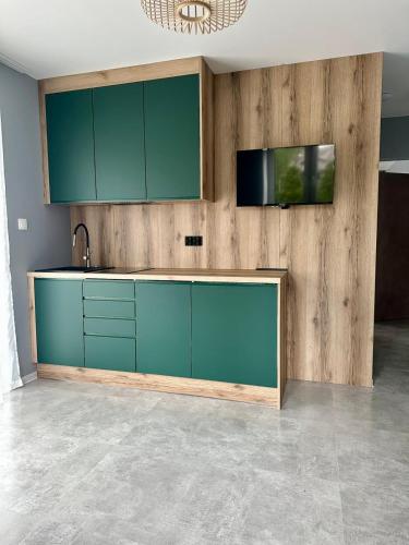 a kitchen with blue cabinets and a tv on a wall at Ramzes 2 in Niechorze