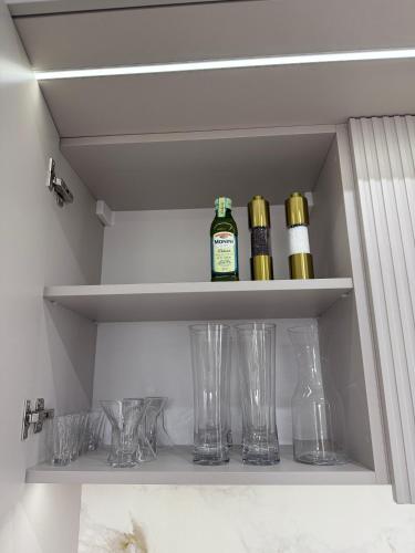 a shelf with wine bottles and glasses on it at GOLD Apartment - Lotnisko Katowice-Pyrzowice in Siewierz