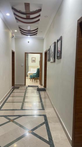 a hallway with a tile floor with a blue chair at Midways Guest House and Hotels in Islamabad