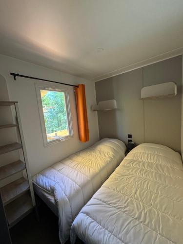 deux lits dans une petite pièce avec une fenêtre dans l'établissement Bungalow, à Gassin