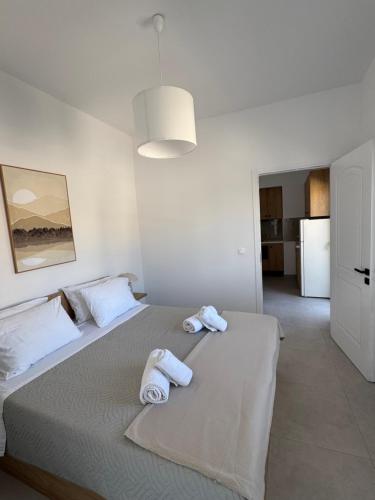 a white bedroom with two towels on a bed at Creta Apt Mela Β5 in Thérissos