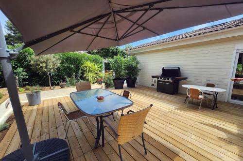 un patio avec une table, des chaises et un parasol dans l'établissement Chalet Californien rénové, superbe piscine dans la résidence, central, ST Tropez 7km!, à Gassin