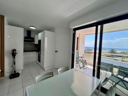 - une cuisine avec une table et des chaises et une vue sur l'océan dans l'établissement Sea Blue Les Roches Marines, au Cap d'Agde