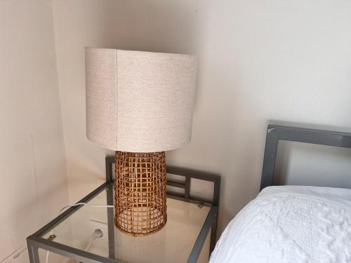 a lamp on a glass table next to a bed at Cocon à Coty in Le Havre