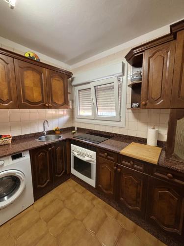 eine Küche mit Holzschränken, einer Spüle und einem Geschirrspüler in der Unterkunft Piso en el precioso pueblo de Colunga in Colunga