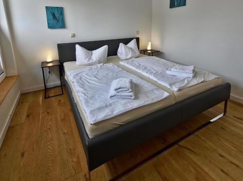 a large bed with white sheets and towels on it at Fischstübchen Neeberg Fewo 4 – Schwalbennest in Krummin