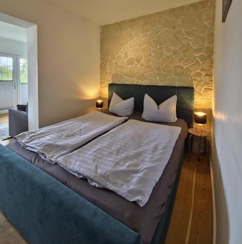 a bedroom with a large bed with a stone wall at Fischstübchen Neeberg Fewo 5 – Bootshaus in Krummin