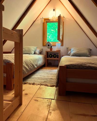 a attic bedroom with two beds and a window at Brvnara Vrganj in Savinac