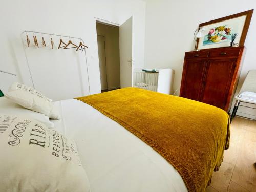 - une chambre avec un grand lit blanc et une couverture jaune dans l'établissement Liberté - Grand appartement 4 pers avec parking Lille Centre, à Lille