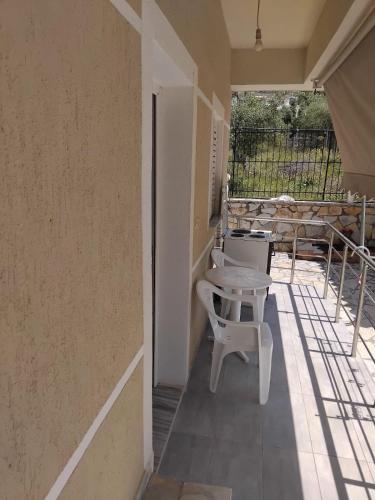 a porch with two white chairs and a table at Rexhos Studios in Himare