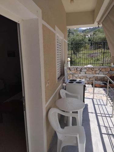 a patio with a table and two white stools at Rexhos Studios in Himare
