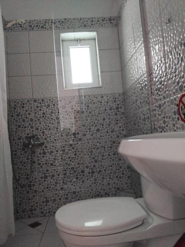 a bathroom with a toilet and a sink and a window at Rexhos Studios in Himare