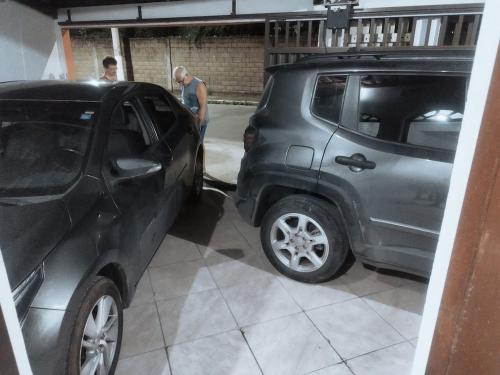 a man standing next to a car in a garage at Minha casa, meu lar! Praia de Jacaraipe ES! in Serra