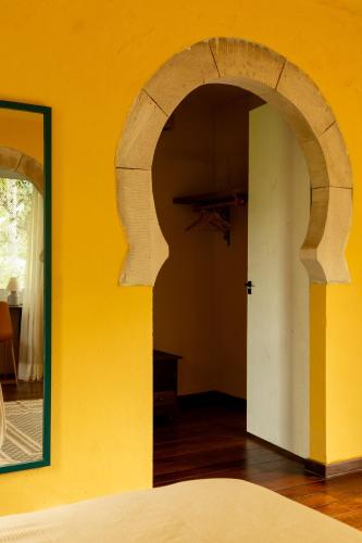 a room with a yellow wall and an open door at O Portalzinho in Paraty