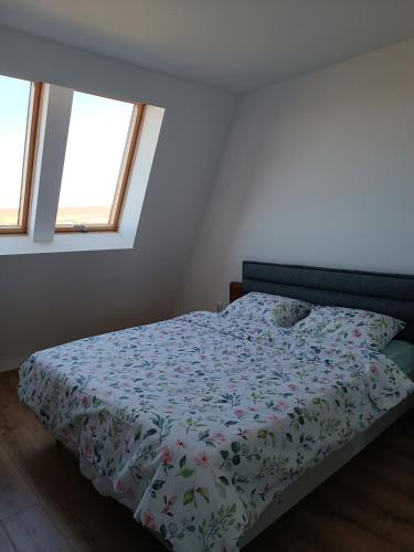 a bedroom with a bed with a floral comforter and two windows at 2 Zimmerwohnung in Shkorpilovtsi