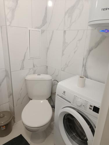 a white bathroom with a toilet and a washing machine at 2 Zimmerwohnung in Shkorpilovtsi