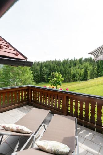 a balcony with chairs and a view of a field at Landhaus Birgbichler - Apartments in Ramsau am Dachstein - inklusive SOMMERCARD! in Ramsau am Dachstein
