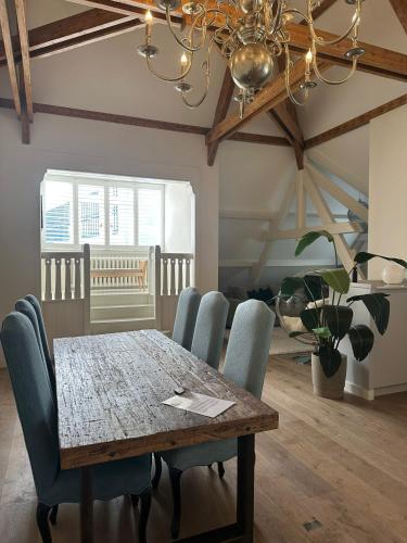 a dining room table with blue chairs and a chandelier at Urban Comfort Loft in The Hague