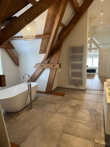 a bathroom with a white bath tub and wooden ceilings at Urban Comfort Loft in The Hague