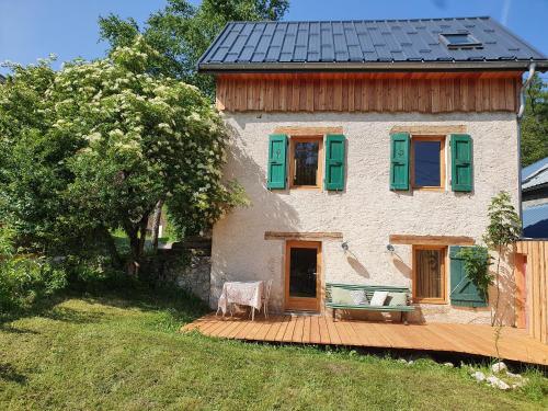 a house with green shuttered windows and a wooden deck at Maison indépendante au pied du Vercors - Gîte du Mas Roux in Château-Bernard
