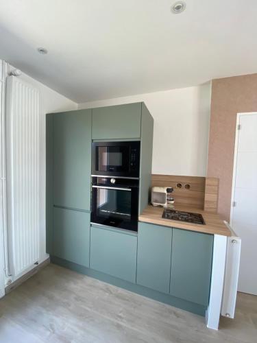 La cuisine est équipée de placards bleus et d'un four avec plaques de cuisson. dans l'établissement Maison à 100 m de la plage, à Pirou