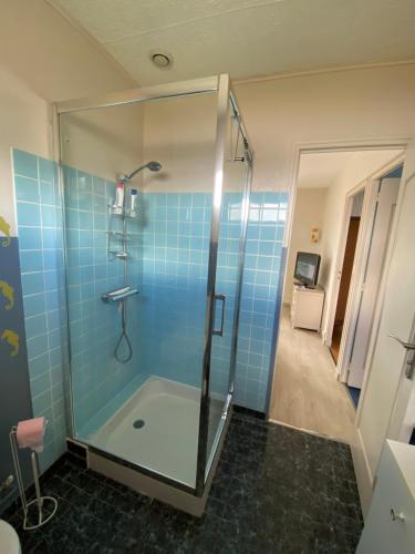 une salle de bain avec douche aux carreaux bleus dans l'établissement Maison à 100 m de la plage, à Pirou