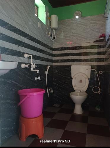 a bathroom with a toilet and a sink and a bucket at Srujana Beach Homestay in Gokarn