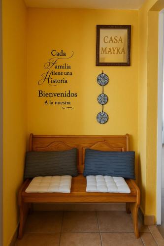 a bench in a room with a yellow wall at Pensión O Muiño in O Pedrouzo