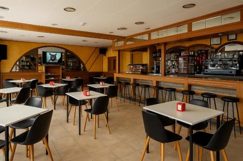 a restaurant with tables and chairs and a bar at Pensión O Muiño in O Pedrouzo