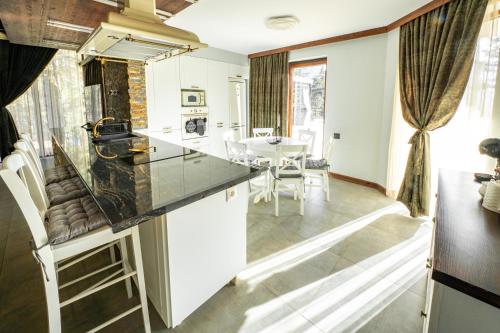 a kitchen with white cabinets and a table and chairs at Планинска вила АЛТЕА in Mostowo