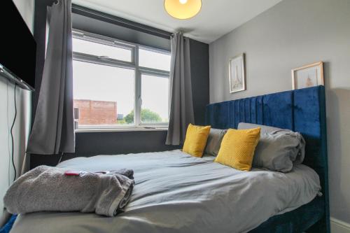 a bed with a blue headboard in a room with a window at 2 Bedroom Property In City Centre by Prestige Lets in Bristol