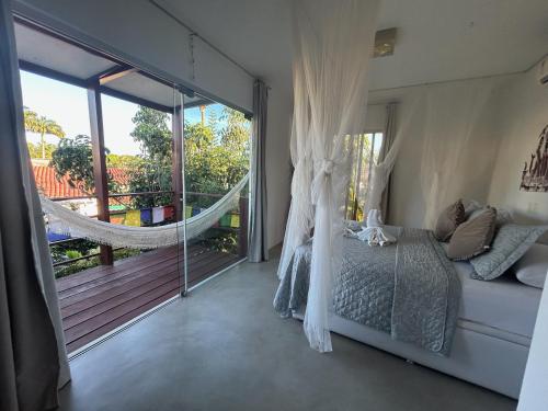 Un dormitorio con una cama y una hamaca en un balcón. en La Reserve Design Villa IDA, en Pipa
