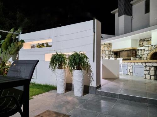 two white vases with plants in them on a patio at Casa di Jiovanni Luxury in Asgourou