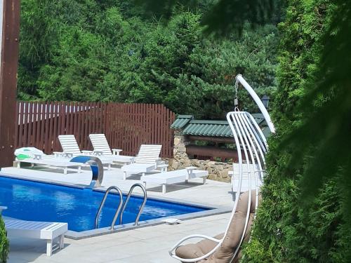 a swimming pool with white chairs and a slide at Hotel & Apartments G S in Mykulychyn