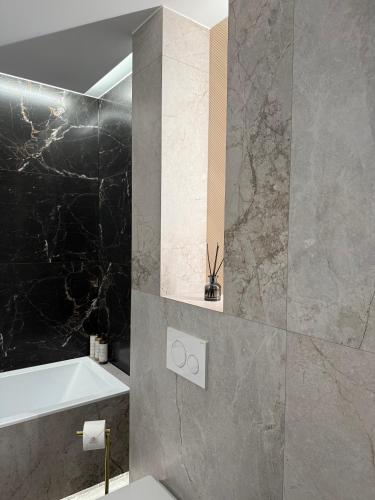 a bathroom with a black and gray marble wall at GOLD Apartment - Lotnisko Katowice-Pyrzowice in Siewierz